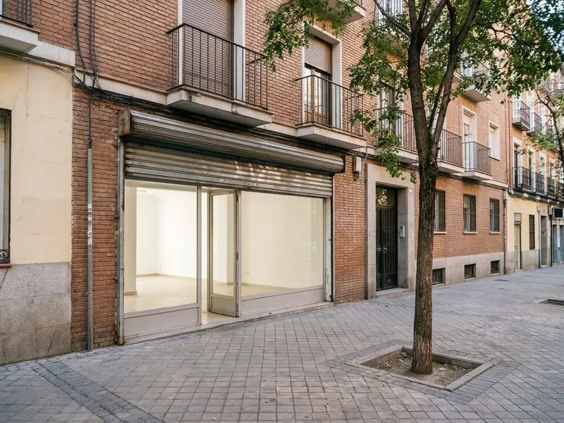 Local comercial vacío a pie de calle con el escaparate limpio y la persiana medio subida